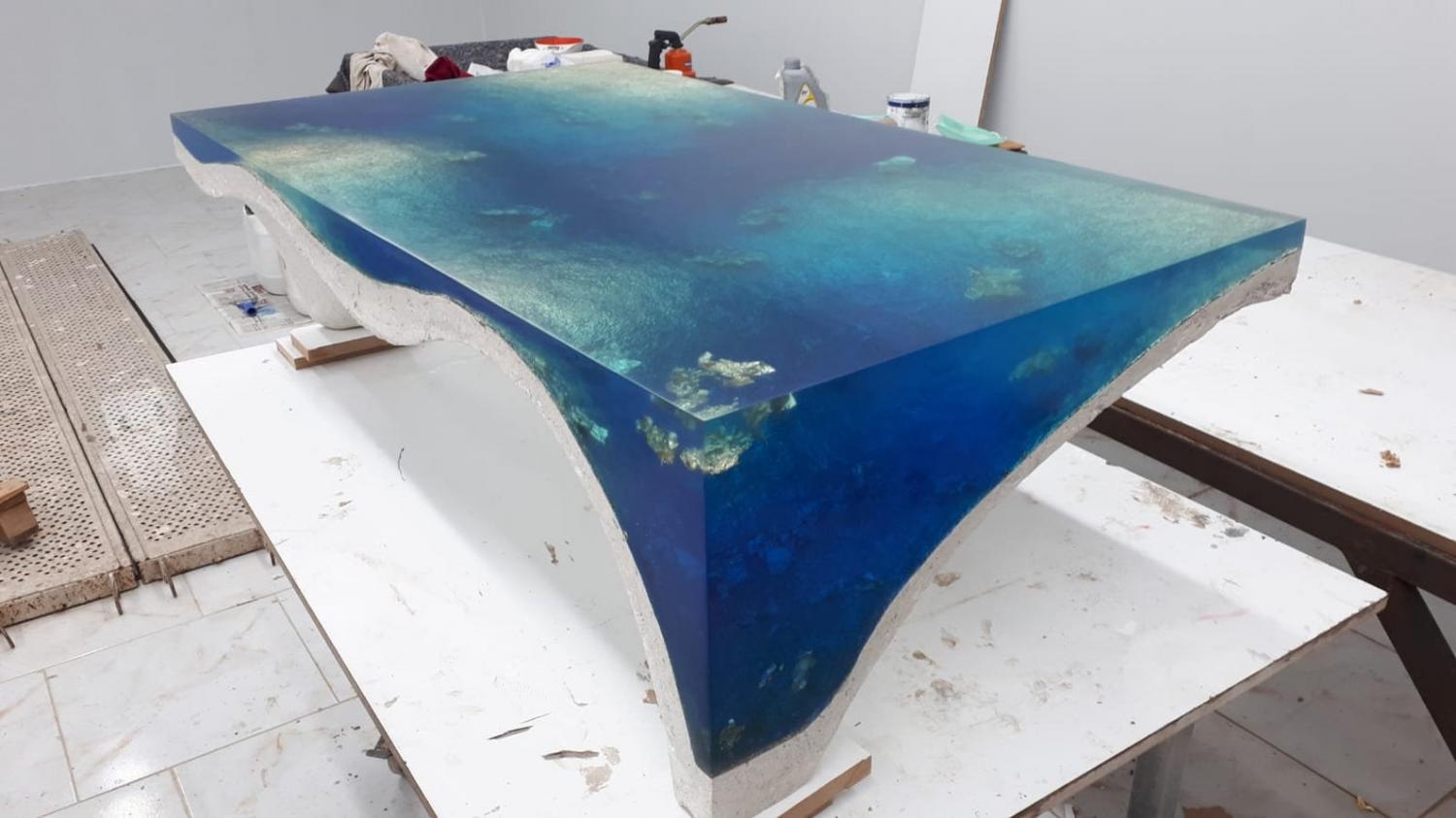 luxury table is a concrete sculpture and filled with epoxy to give stunning illusion of looking into a deep dark blue sea