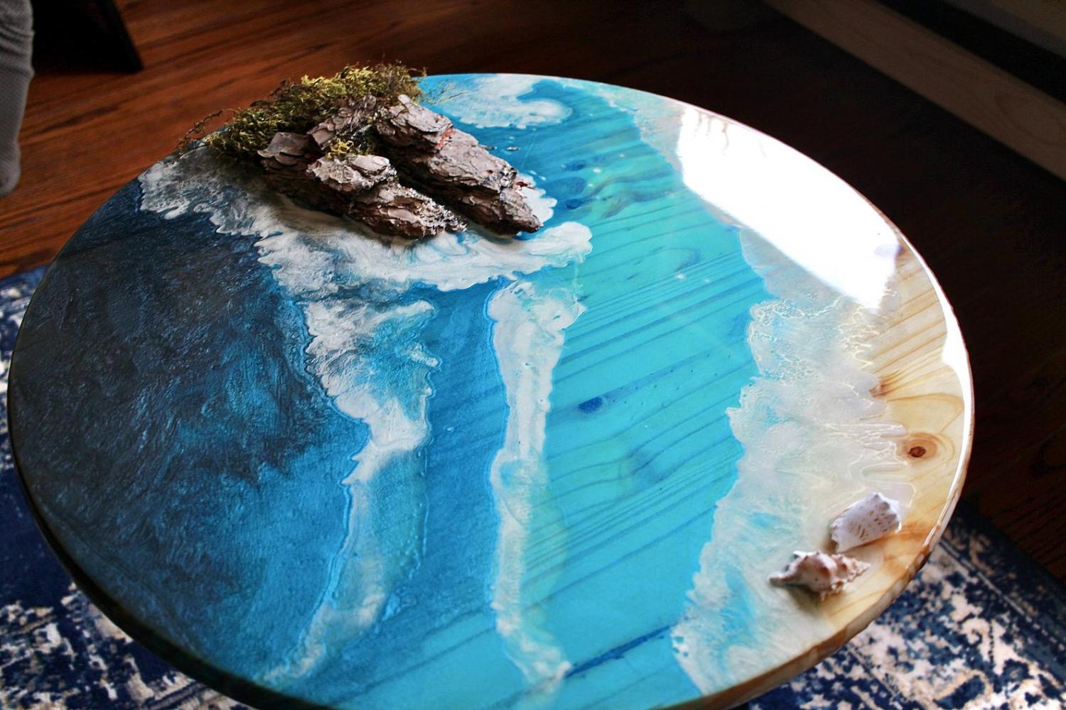 A circular epoxy table made to look like the shore of an ocean