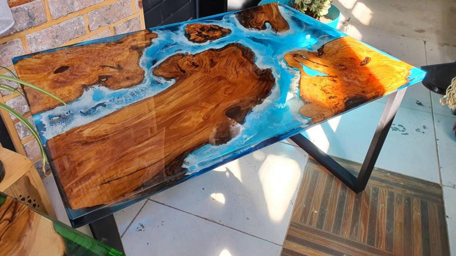 A similar epoxy table with bright blue waters surrounding islands made from olive wood